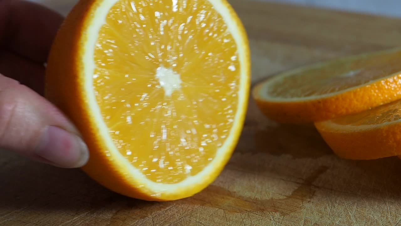 新鲜多汁的橘子用菜刀在木砧板上切。视频素材