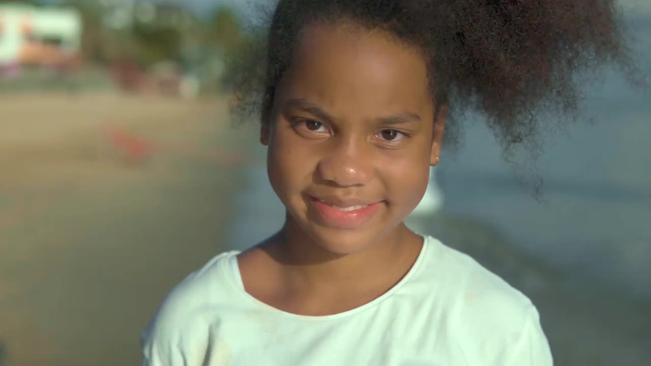 小女孩的视频微笑，看着相机在海滩度假。视频素材