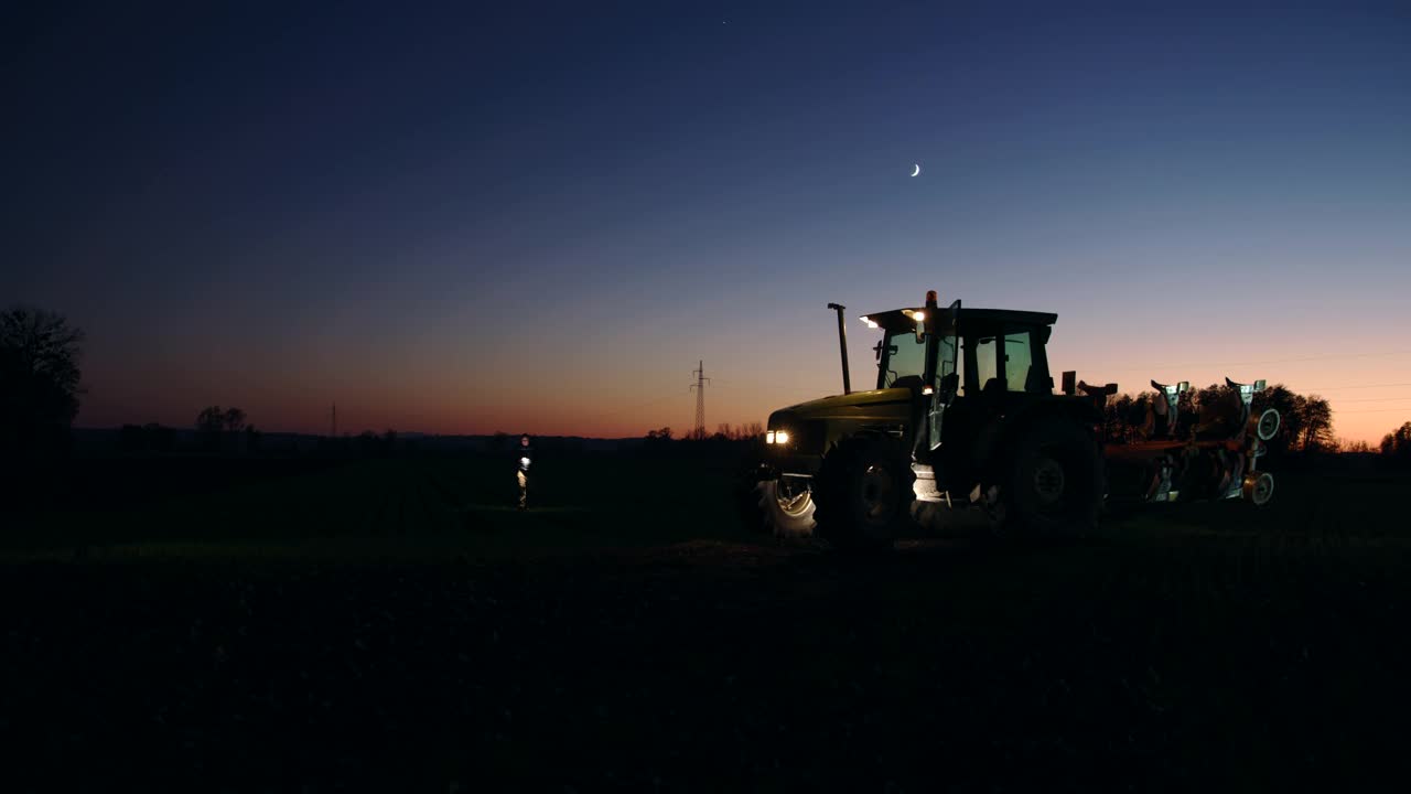 晚上，一个面目人非的农民走回田里的拖拉机旁视频下载