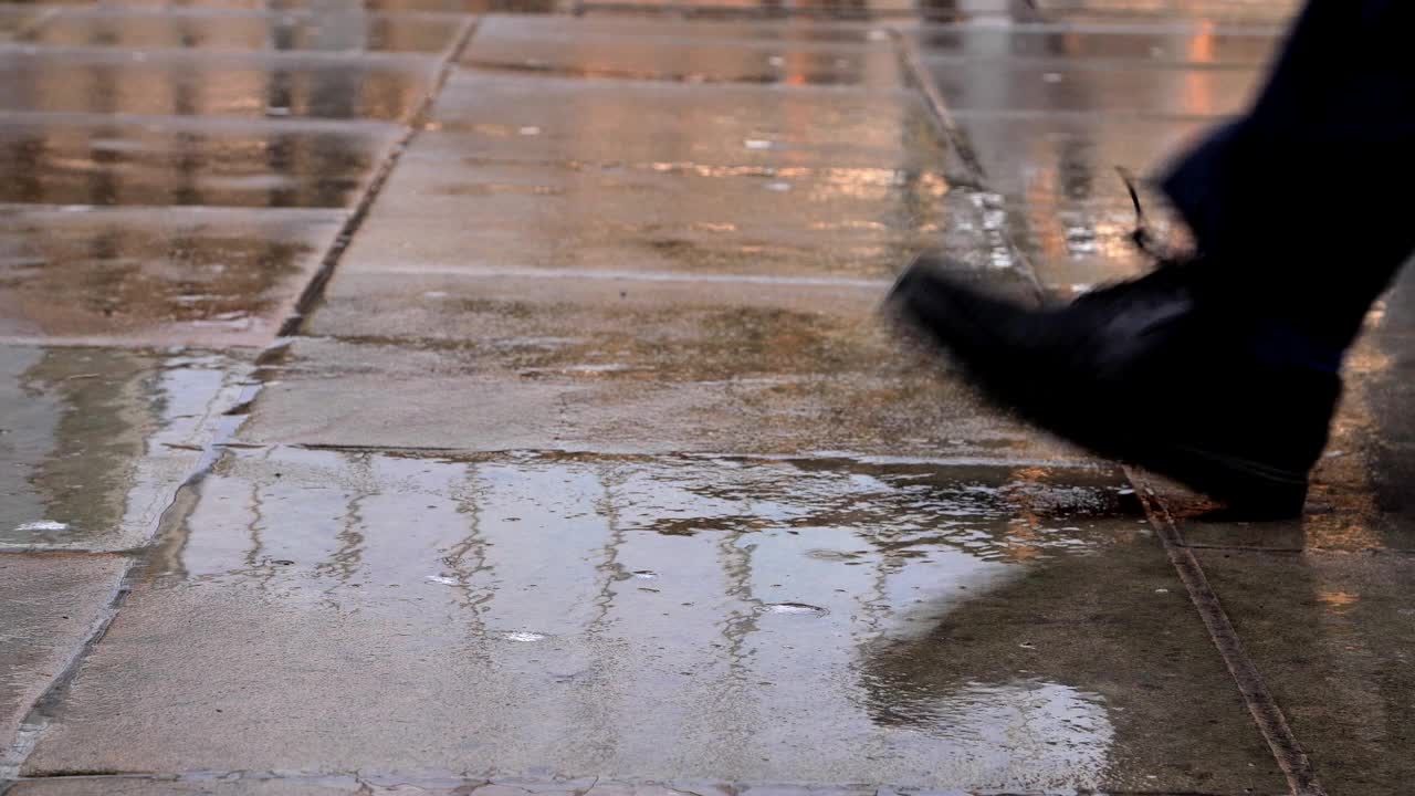 两只脚和在雨中撑着雨伞的通勤者。视频素材