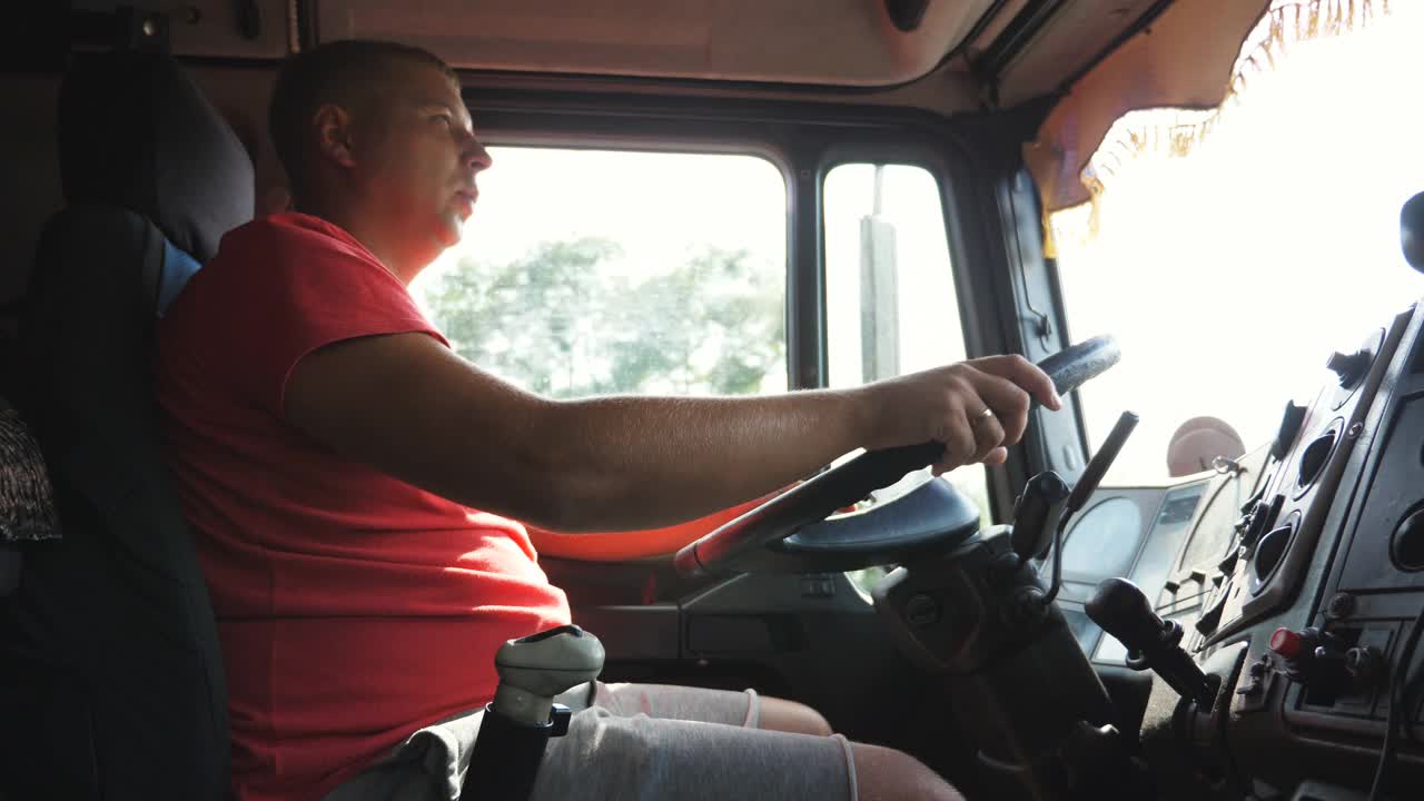 卡车司机开车穿过乡村，用无线电交谈。卡车司机在乡村公路上开车时用对讲机说话。物流运输理念。慢动作视频下载