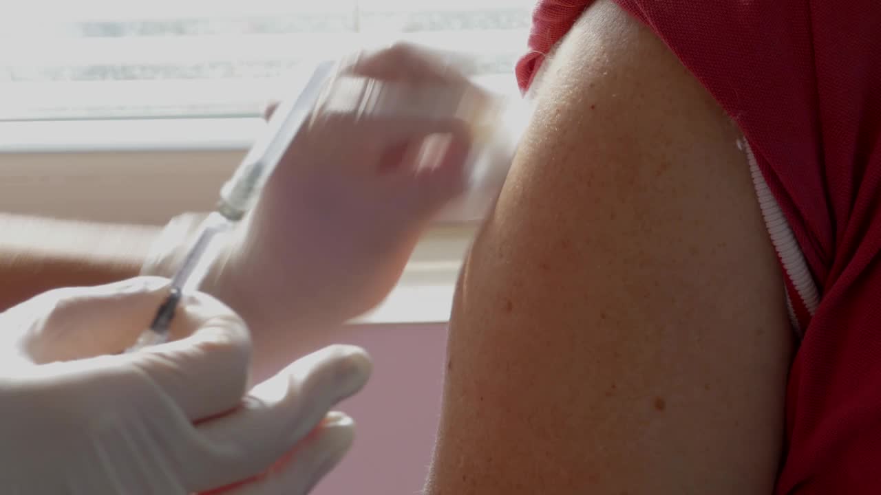 4K视频:医护人员为一个人接种疫苗，以预防COVID-19大流行疾病。视频素材