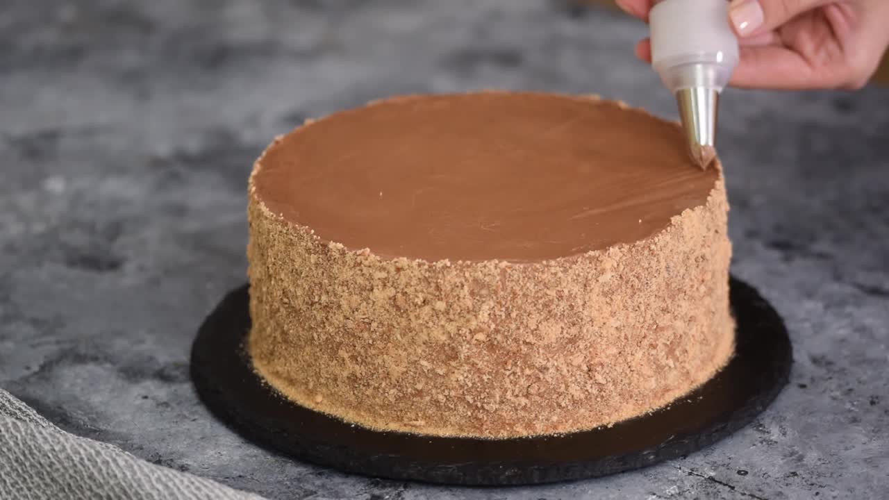 女人拿着糕点袋在厨房用巧克力奶油装饰蛋糕视频下载