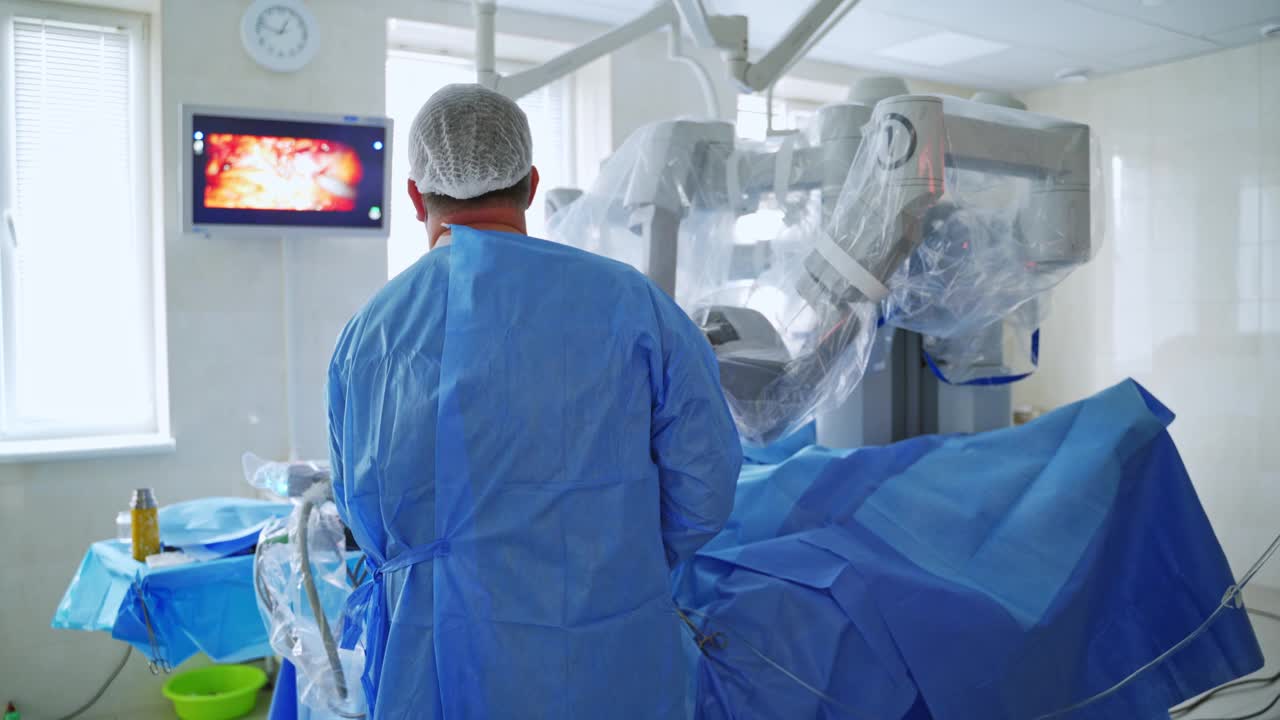 医生用手术机器人做手术。在现代诊所的机器人手术期间，外科医生看着监视器的后视图。视频素材