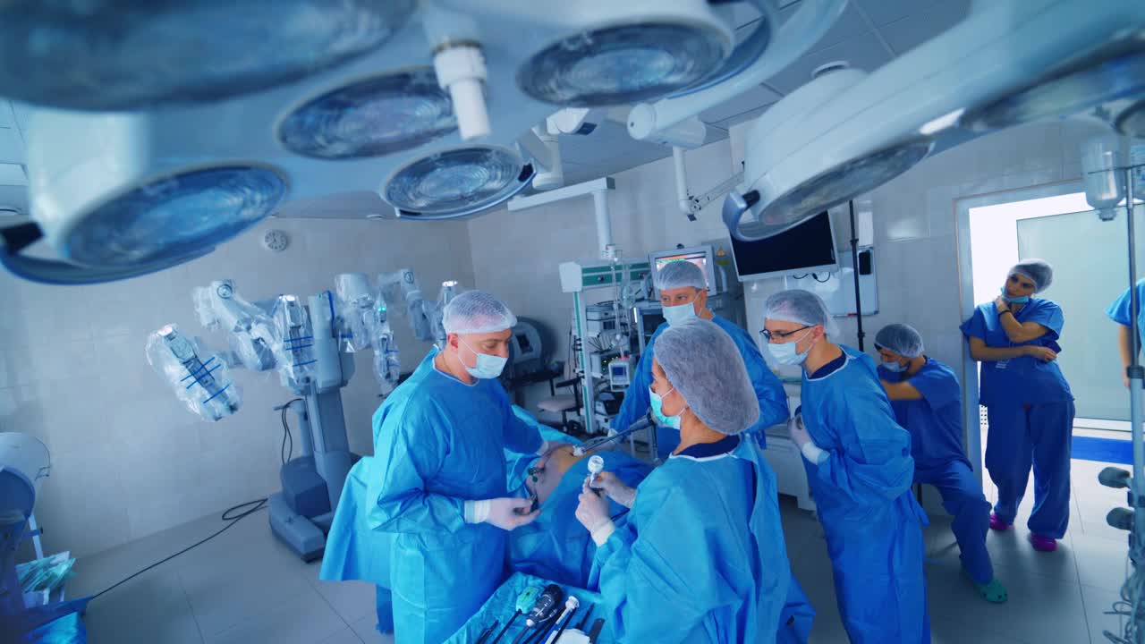 身穿蓝色制服的医护人员在手术室里。许多外科医生用新的医疗技术给病人做手术。创新药物。视频素材