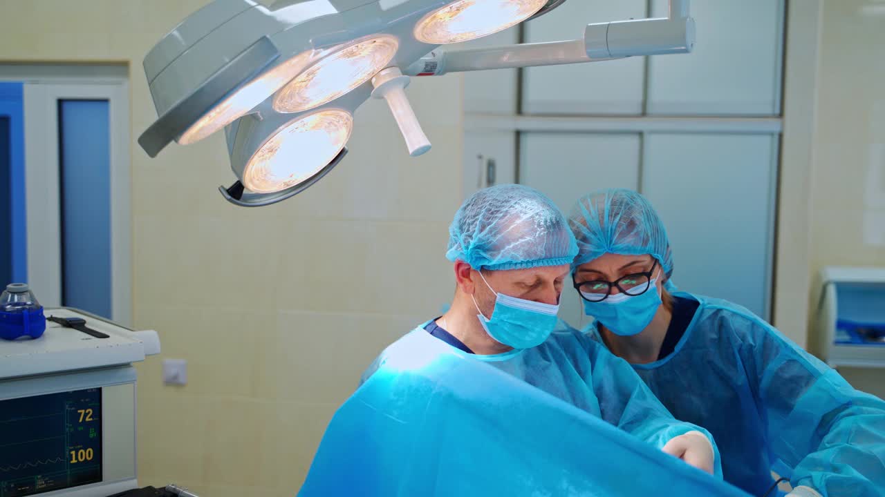 外科医生和护士在诊所做手术。身着制服的专业医生和助手在现代手术中心进行手术。视频素材