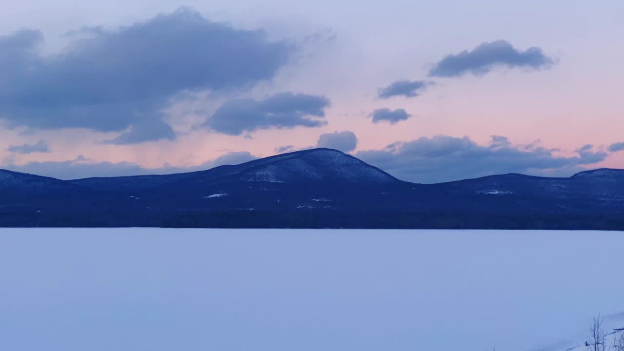 日落时，冰冻的山湖和远处的山脉视频素材