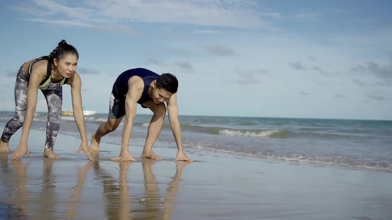 一对年轻的亚洲夫妇在海滩上跑步或慢跑的镜头。视频素材