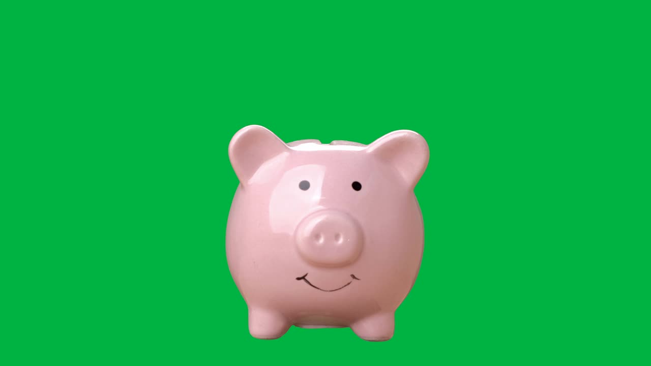 手正把硬币或钱放在存钱罐上，色键绿色屏幕背景。存钱的概念。视频素材