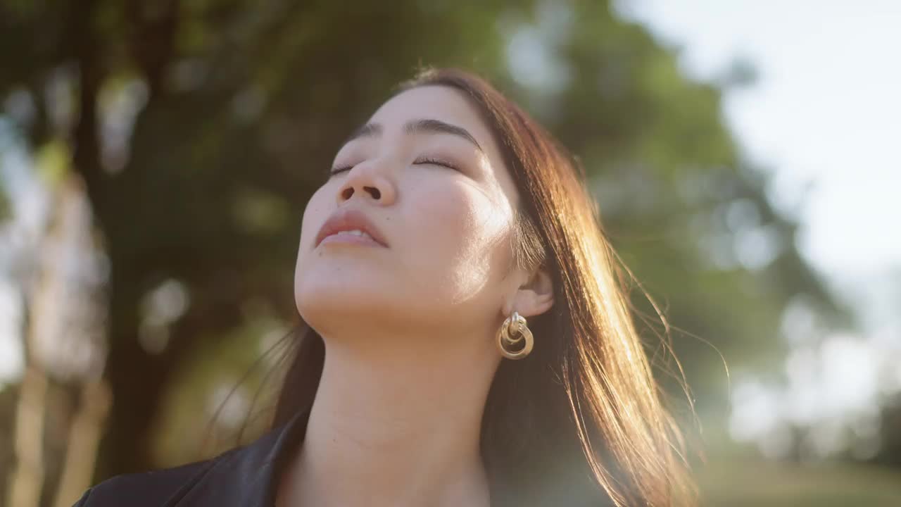 一幅年轻女子闭着眼睛在大自然中放松的肖像视频素材