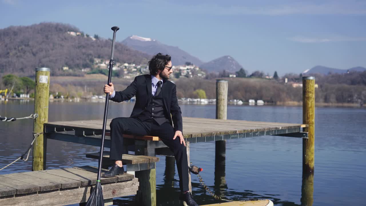 西装男在码头上拿着立桨板放松视频下载