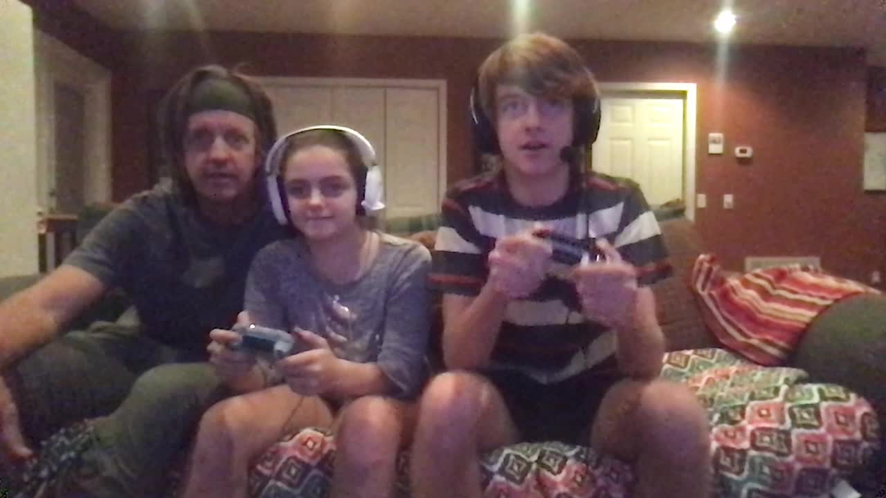 哥哥和妹妹一起坐在沙发上玩多人在线视频游戏，而他们的爸爸在一旁为他们欢呼视频素材