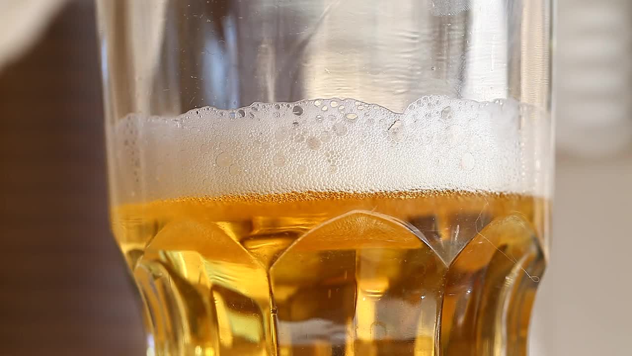 淡啤酒与白色泡沫在玻璃玻璃旋转，旋转。视频素材