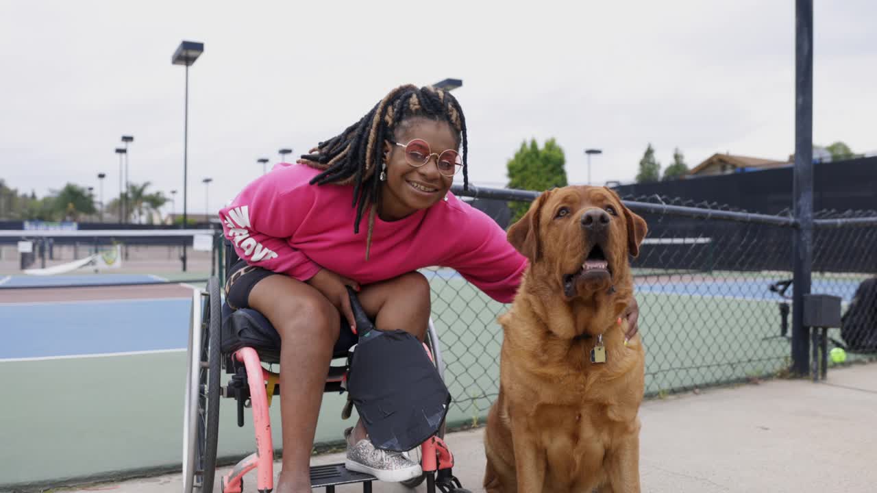 年轻的黑人残疾妇女在轮椅上与朋友玩皮球视频下载