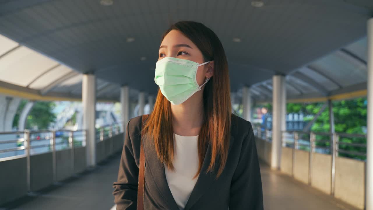 在新冠肺炎疫情中，亚洲女商人戴着防护口罩上班视频下载