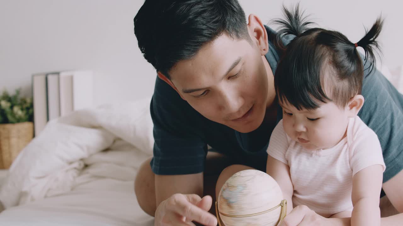 笑着的宝宝和爸爸一起学习全球。视频购买