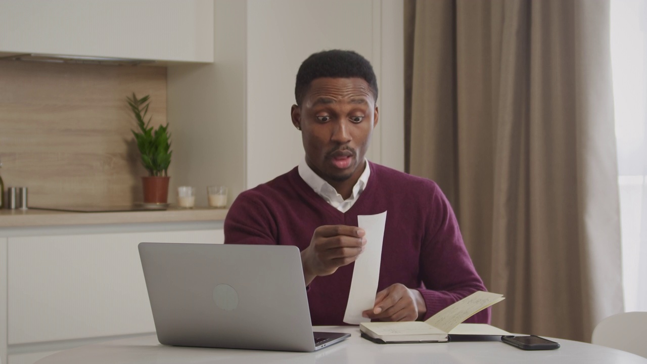 年轻的非洲裔美国人检查他的账单和管理家庭开支视频下载