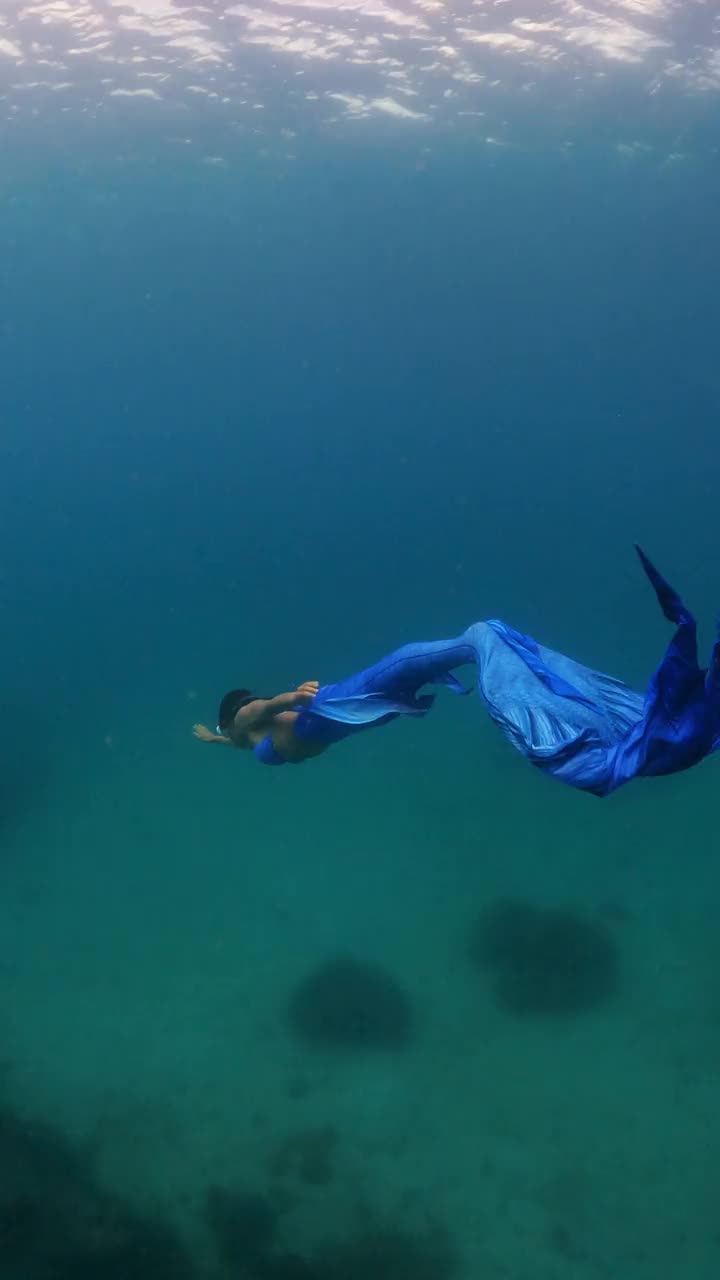 亚洲妇女穿着美人鱼的服装，在清澈的海水中潜水视频下载