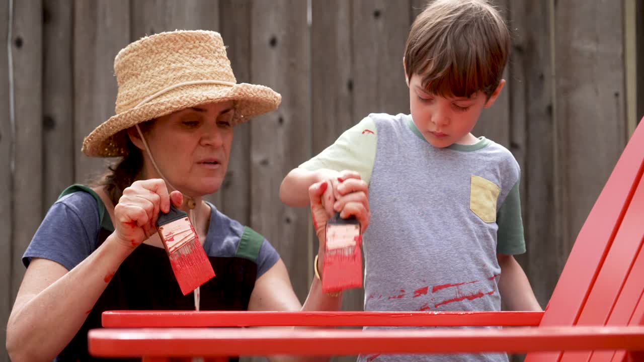 一个成熟的女人和她的儿子在自家后院画沙滩椅视频素材