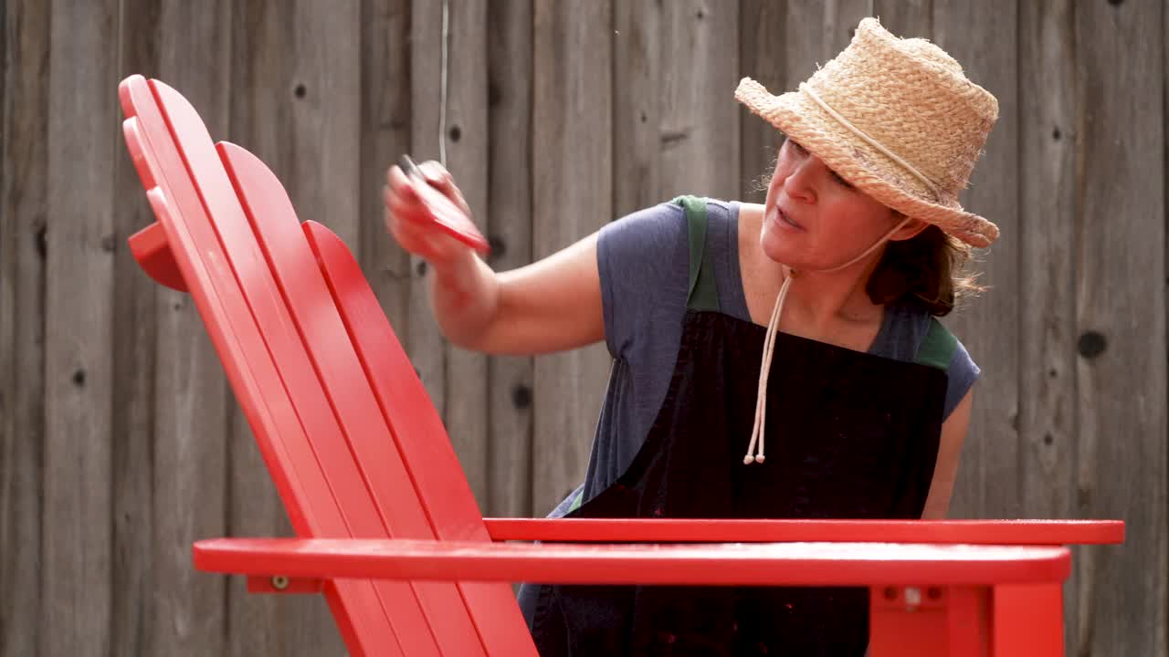 一个成熟的女人在自家后院画沙滩椅视频素材