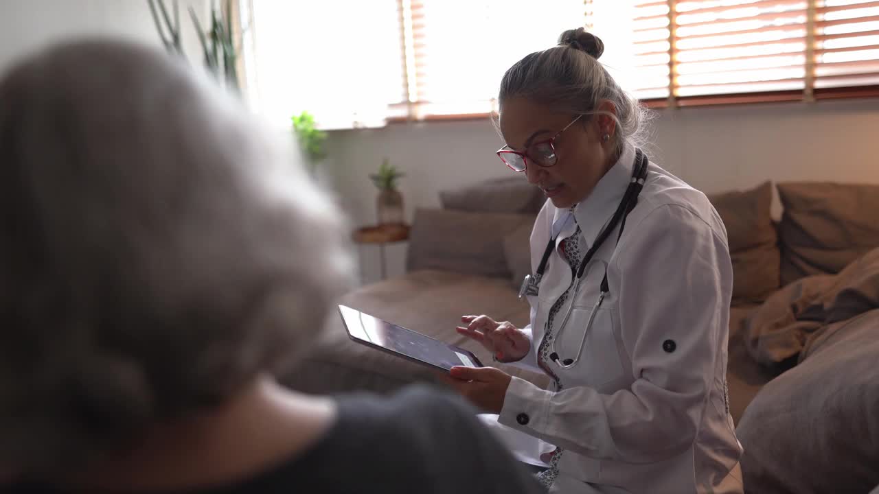 医生在家访中使用数字平板电脑与老年患者交谈视频素材