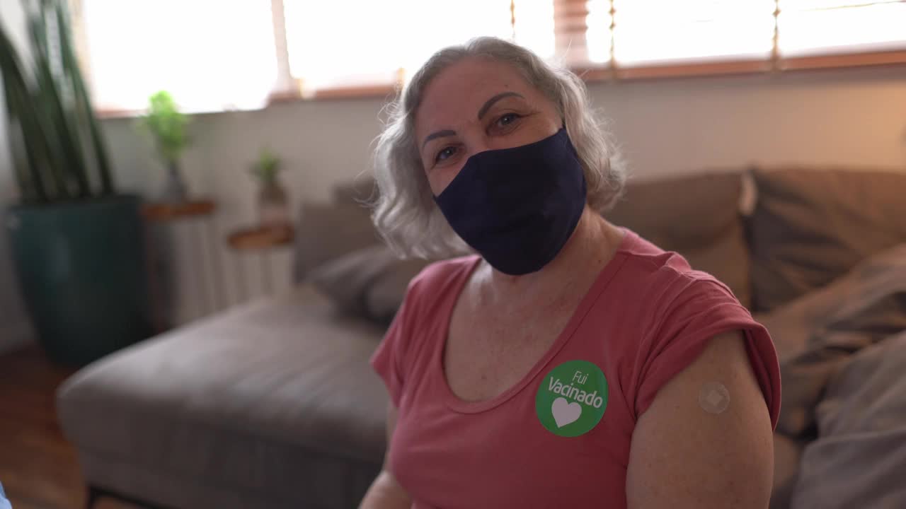 一位年长妇女的肖像与“Fui vacinado”(接种疫苗)贴纸戴口罩视频下载