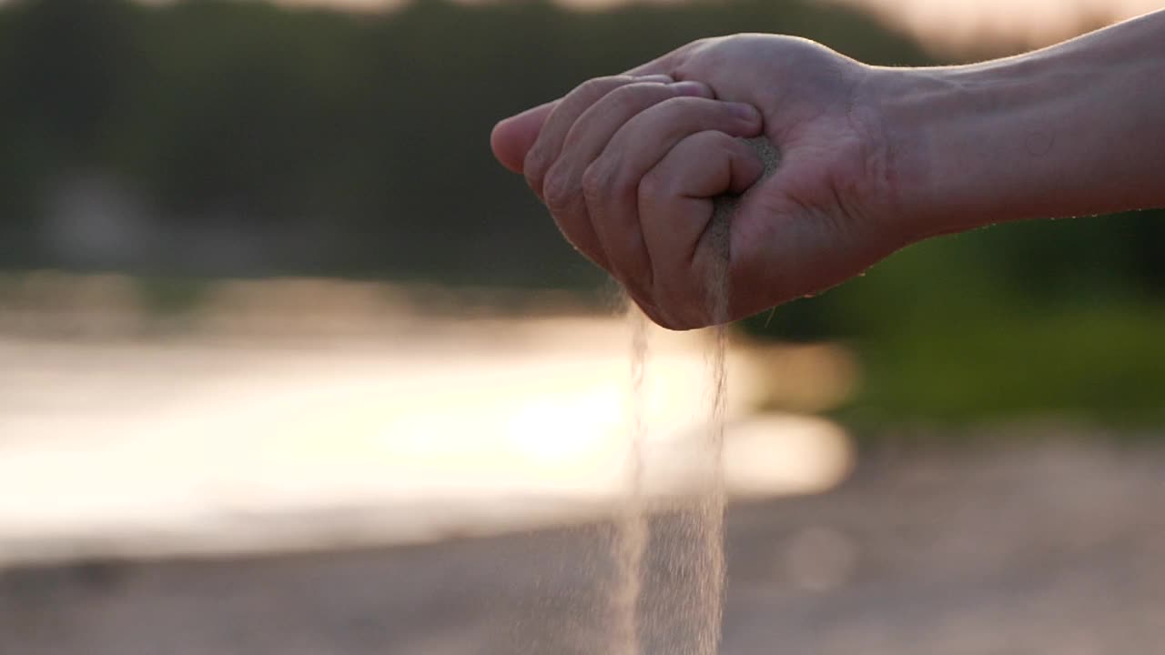 沙子从一个旅行者的手指间慢慢落下的动作视频下载