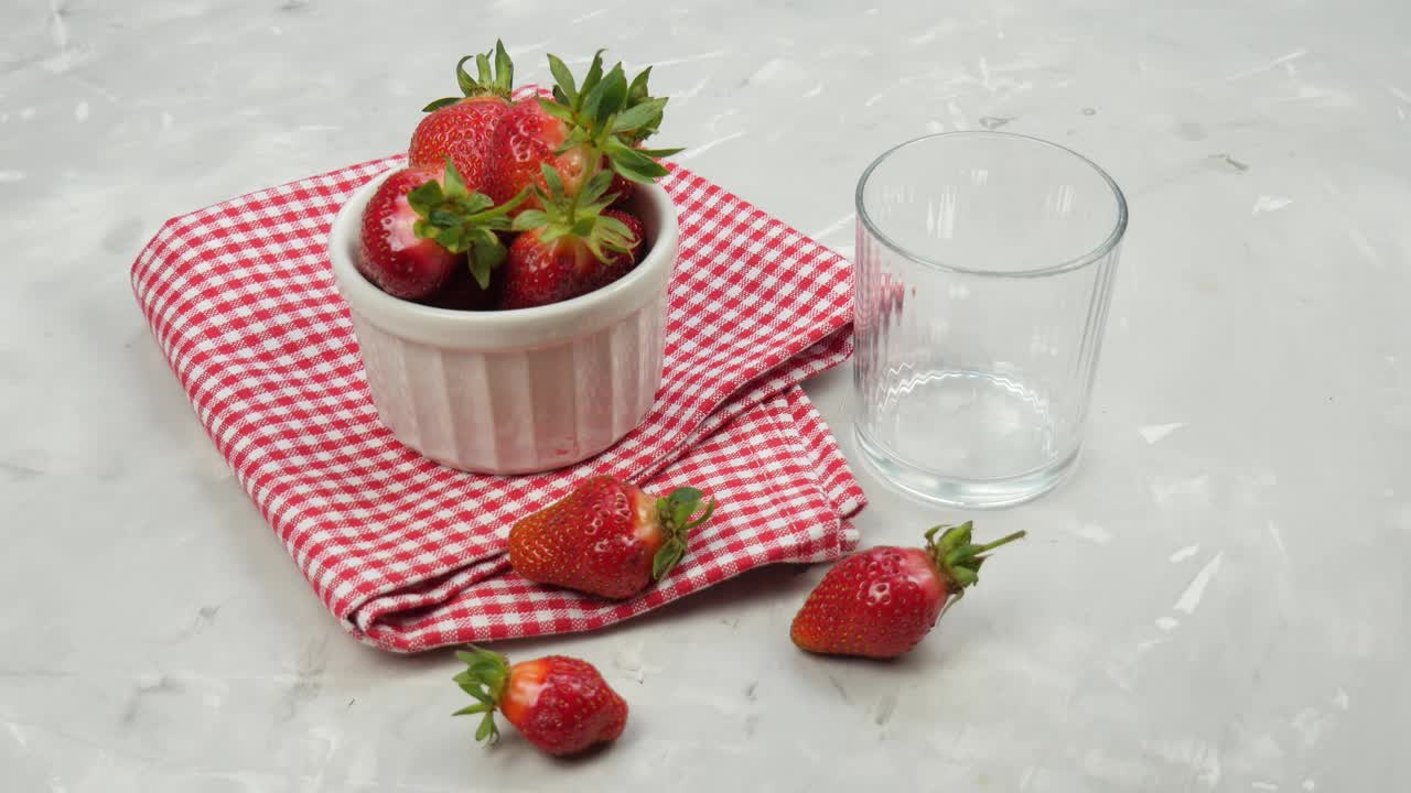倒牛奶。玻璃杯里的生草莓奶昔。健康清爽的夏季素食奶昔。成熟多汁的草莓。4 k视频素材