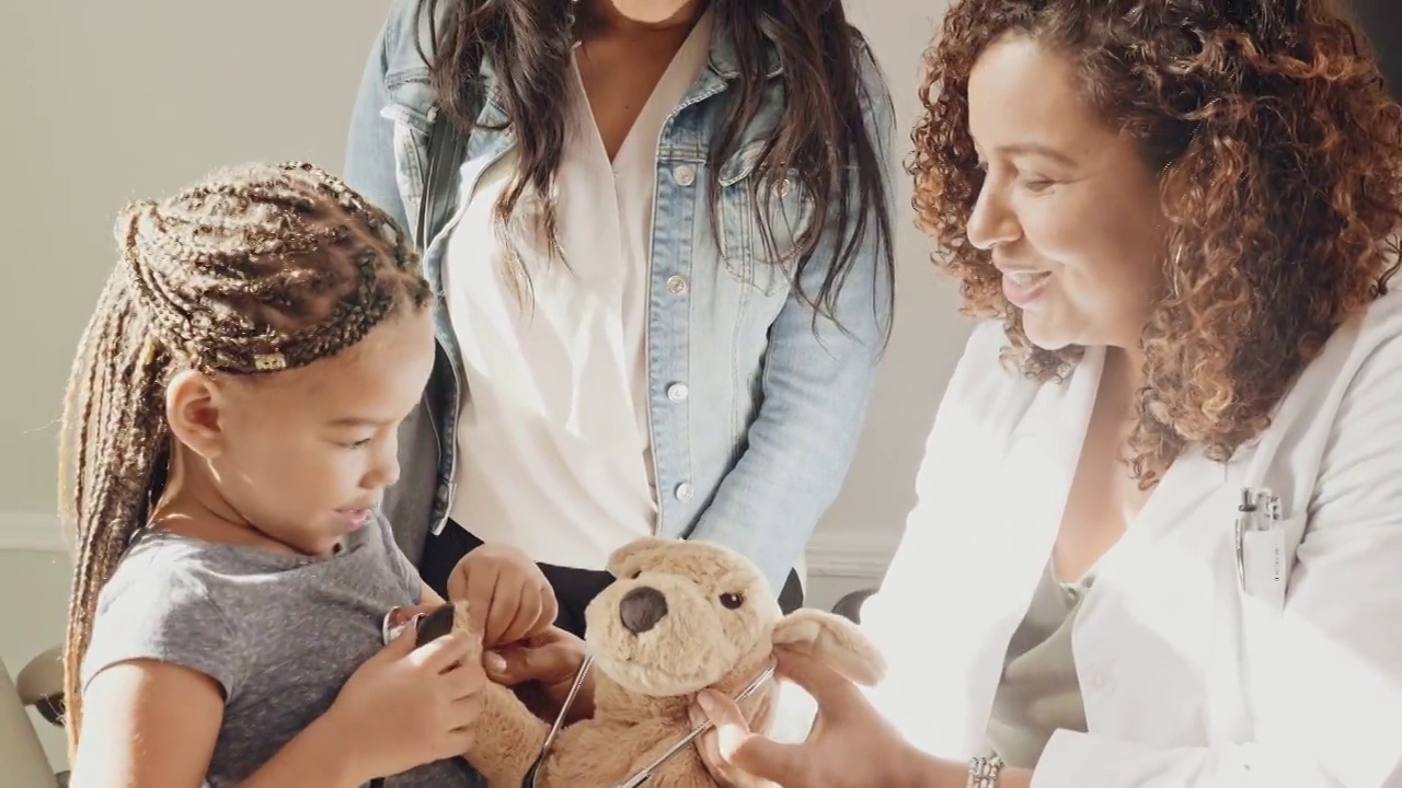 开朗的儿科医生用毛绒玩具帮助孩子在考试时感到舒适视频素材