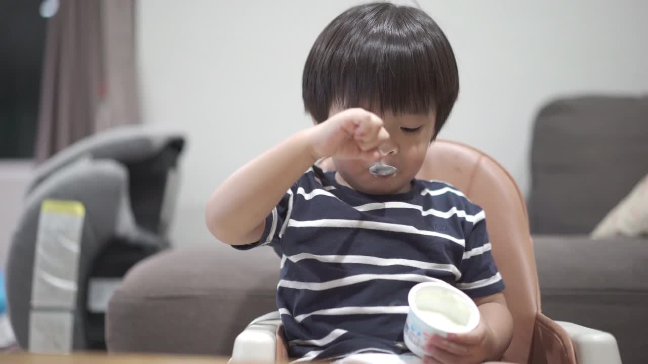 亚洲小男孩在家里的客厅里独自吃酸奶视频下载
