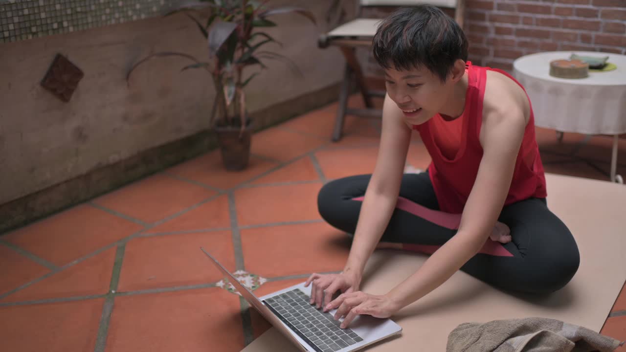 亚洲华人中年妇女练习视频在线训练哈达瑜伽教练现代笔记本冥想苏哈沙那姿势放松呼吸轻松座位姿势健身房健康的生活方式概念视频下载