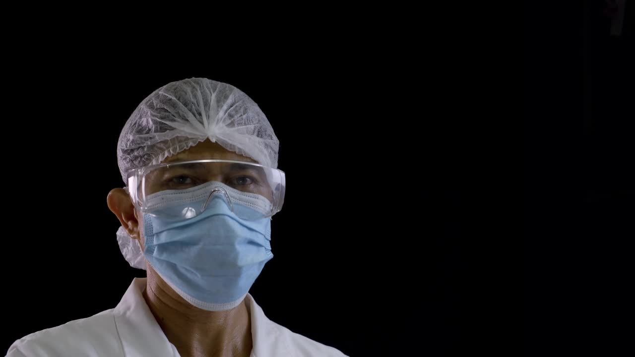 医生戴医用口罩、眼镜和手套，用黑色背景的红外温度计测量病人的温度视频素材