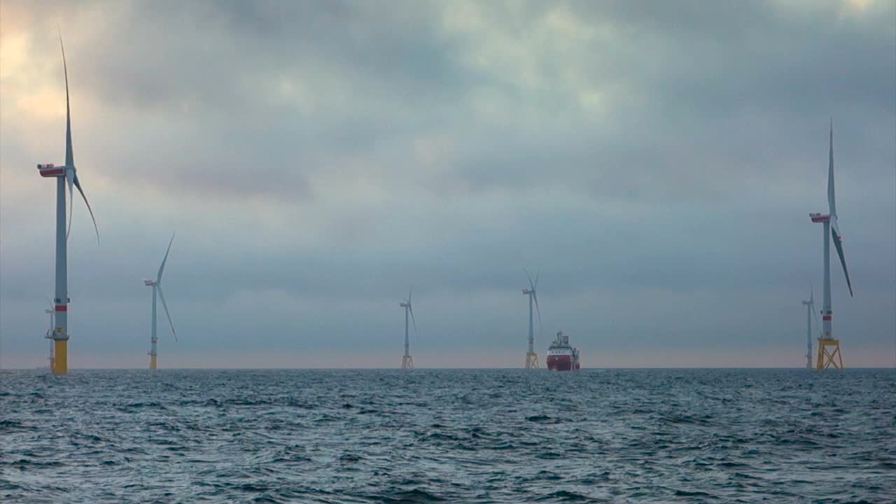 海上风电场，风力发电机水平和大转移船(船，码头)站在它们之间，接缝小，蓝色波浪的大海和喜怒无常，戏剧性的天空。德国，博库姆乐段trung视频素材