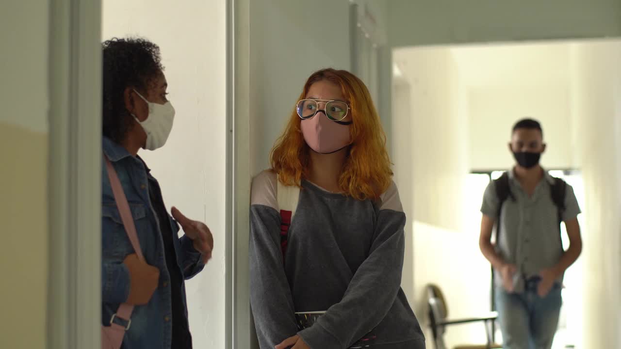 戴着口罩的朋友们在大学走廊里用肘撞来打招呼视频素材