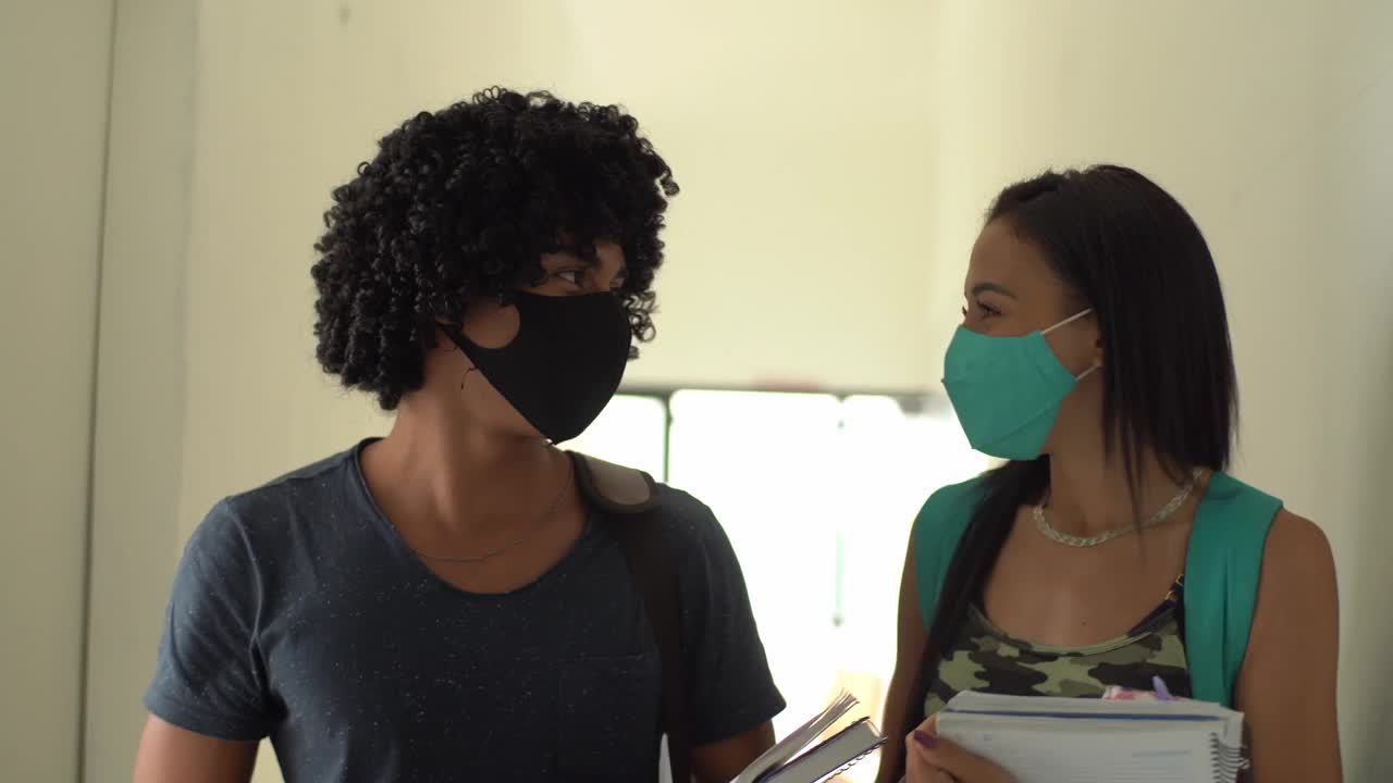 戴着口罩的朋友们在大学走廊里用肘撞来打招呼视频素材