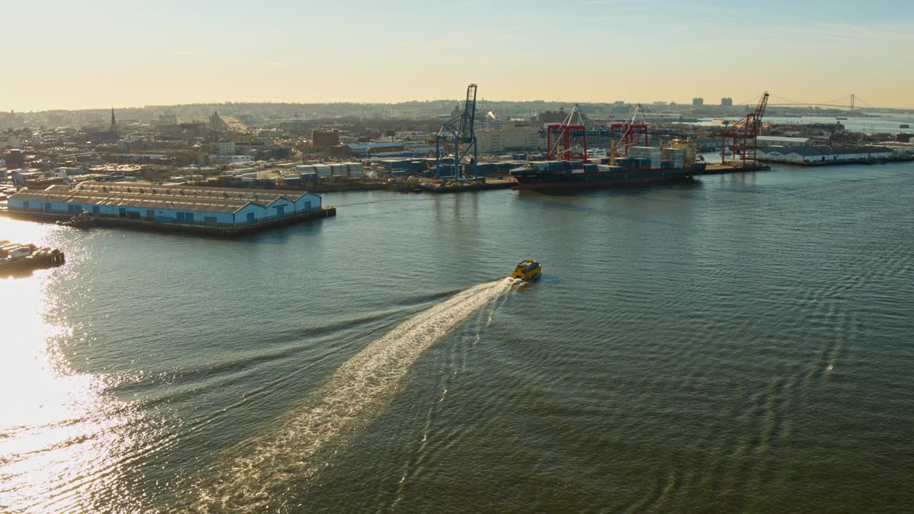 日出时分，纽约布鲁克林商业码头前的水轮正驶过东河。无人机视频与平移摄像机运动。视频下载
