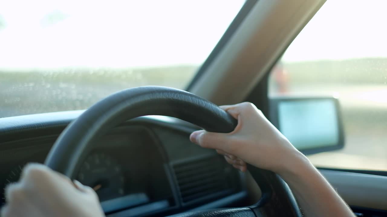女人开着车，她的手放在方向盘上，阳光灿烂视频素材