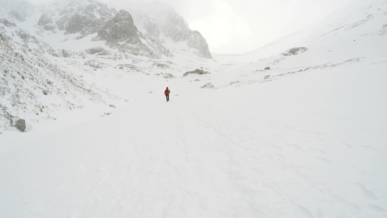 男人在白色条件下爬山的4K动作镜头从后面看视频素材