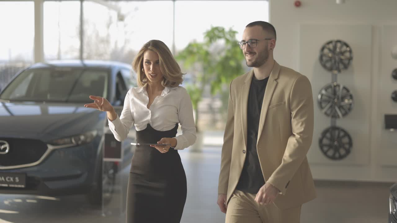 销售女性和男性客户接近汽车和进入，而女性向他展示汽车内饰在汽车经销商视频素材