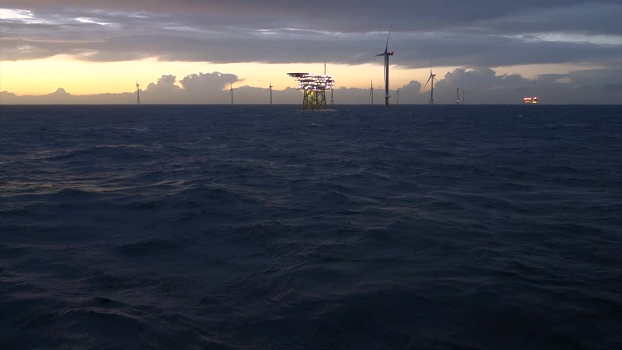 海上风电场，风力发电机与变电站在水平日出，海浪和喜怒无常，戏剧性的天空。德国,Borkum Riffgrund视频素材