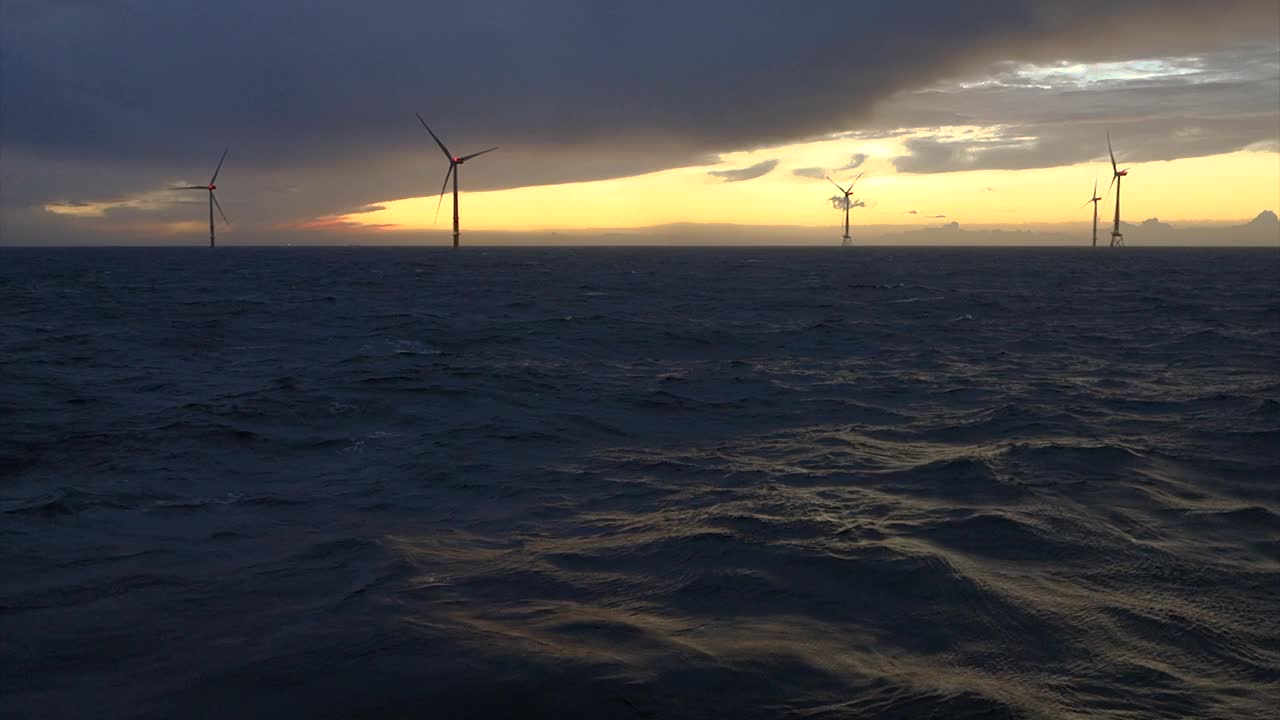 海上风电场和风力涡轮机水平在日落-日出，波浪的海洋和穆迪，戏剧性的天空。德国,Borkum Riffgrund视频素材