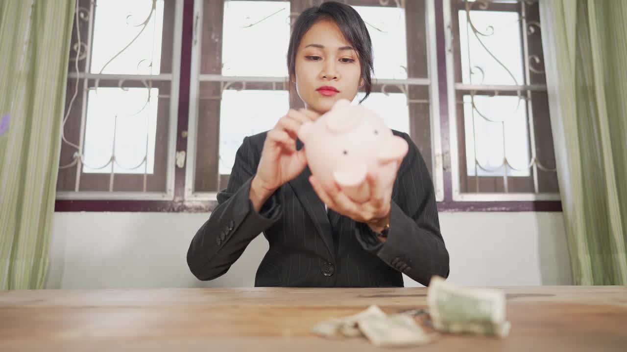 一个女人手里拿着一些硬币要放进存钱罐里存钱。视频素材