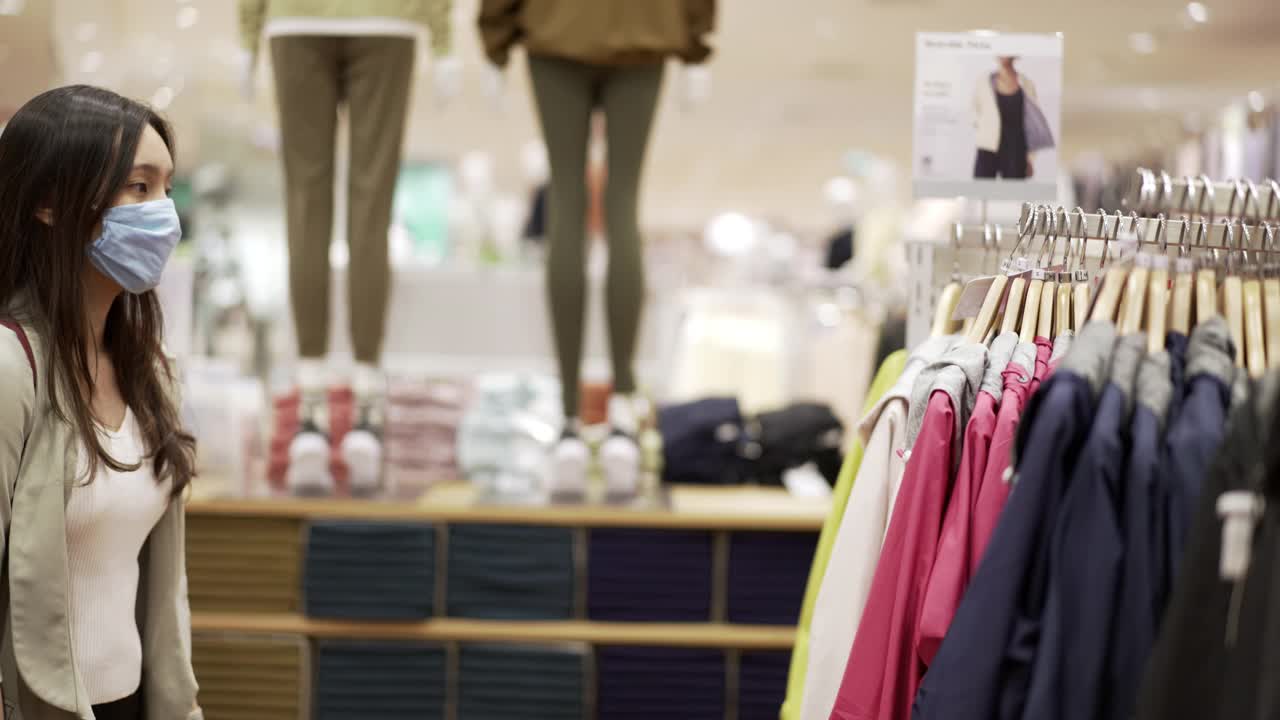 新常态购物，亚洲女性在服装店购物带口罩视频素材