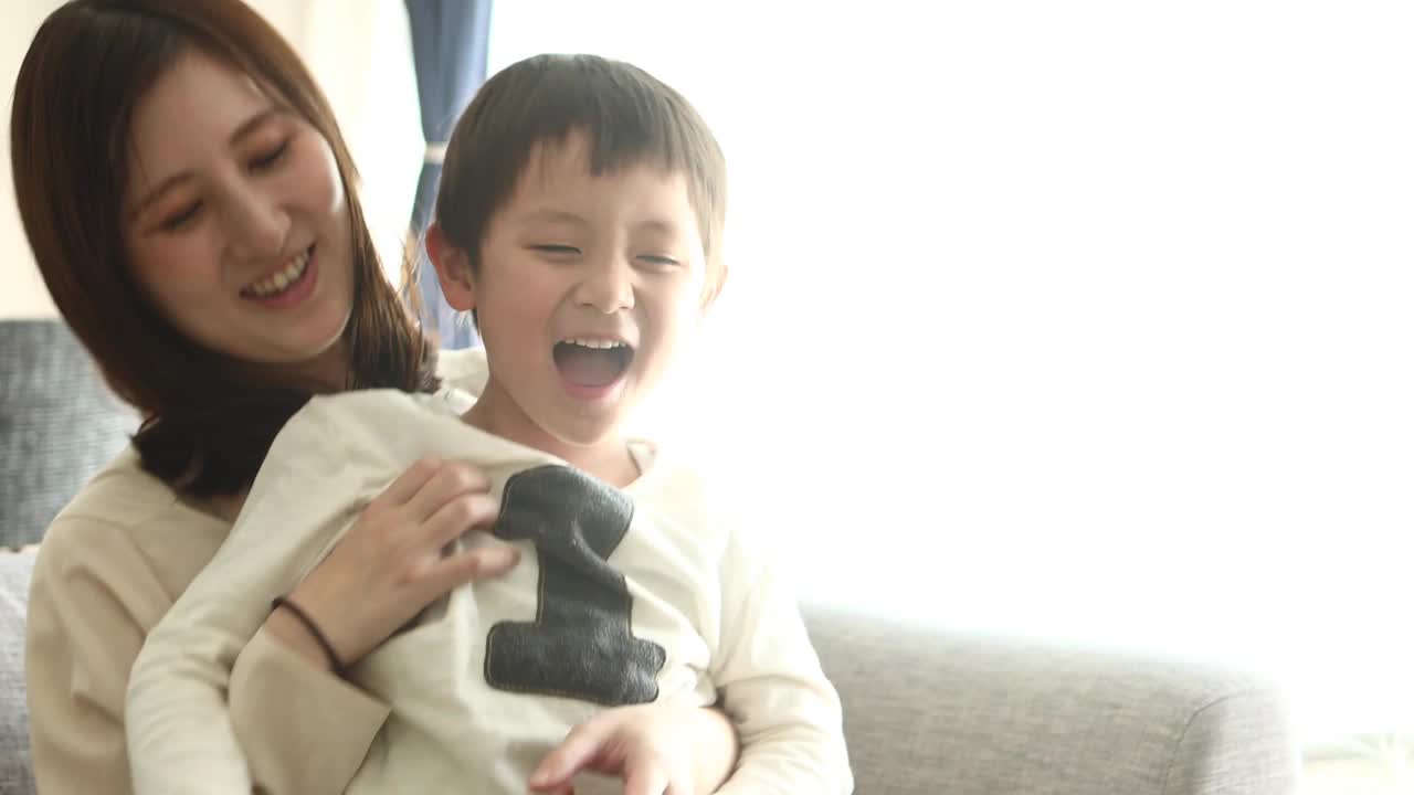 一个男孩和他妈妈在腿上玩视频下载