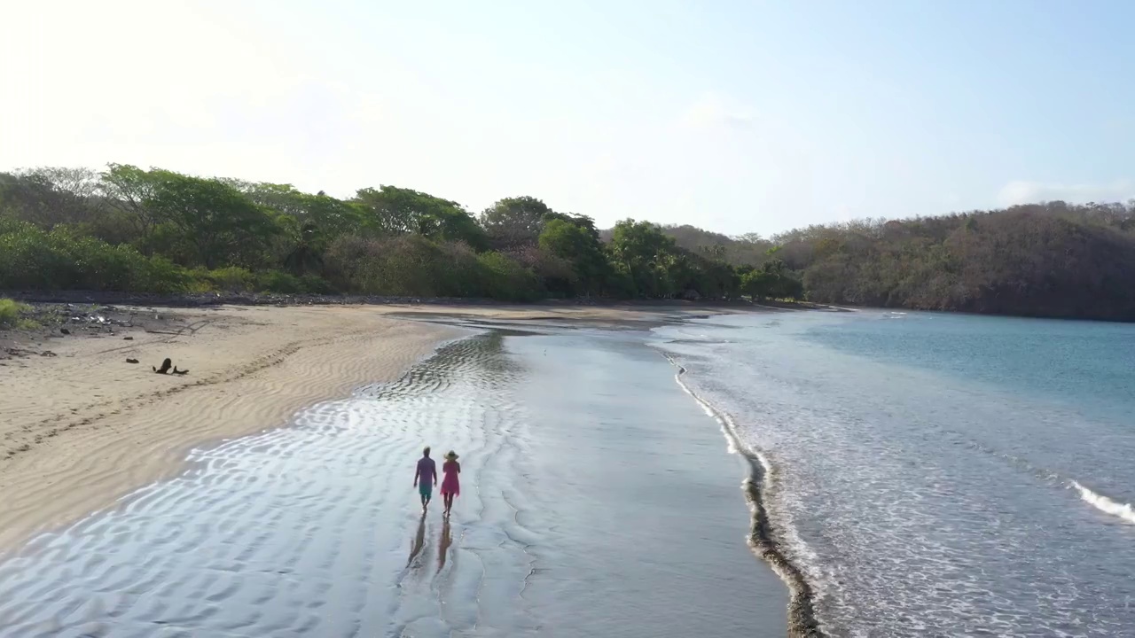 鸟瞰图的成熟夫妇走在空旷的海滩上视频素材