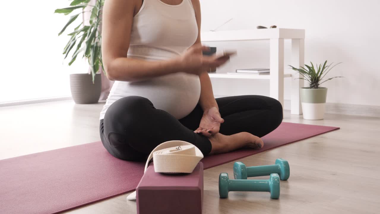 年轻孕妇做放松练习和使用手机。视频下载