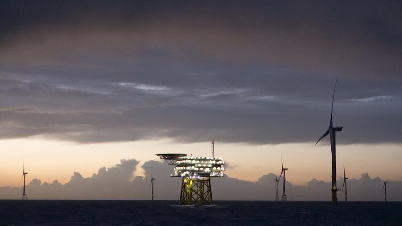 海上风电场的戏剧性的观点，风力发电机与变电站在水平在日落，波浪的海和穆迪，戏剧性的(红色)天空。德国,Borkum Riffgrund视频素材