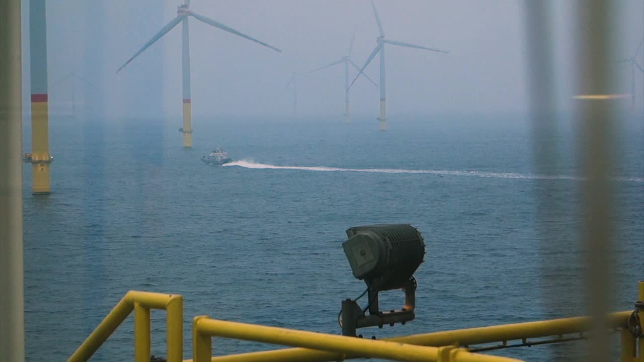 从帆船上看海上风力发电机-风力发电场真窗。在风力涡轮机之间航行的客船视频素材