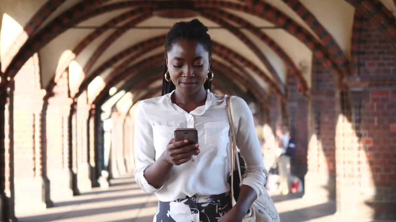 年轻的女游客一边走在城市的人行道上一边发短信视频素材