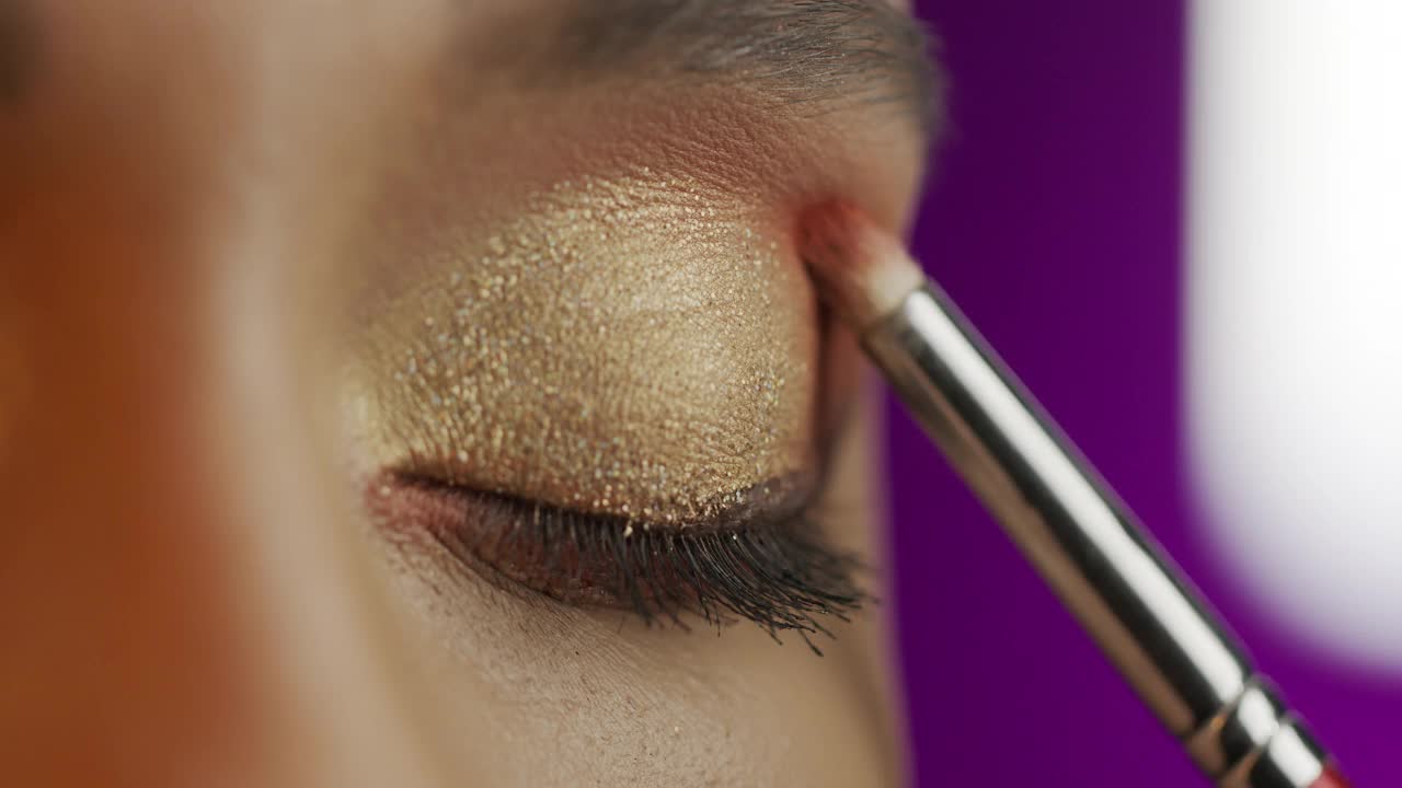 一个女孩用化妆刷涂上橙色眼影的特写。视频素材